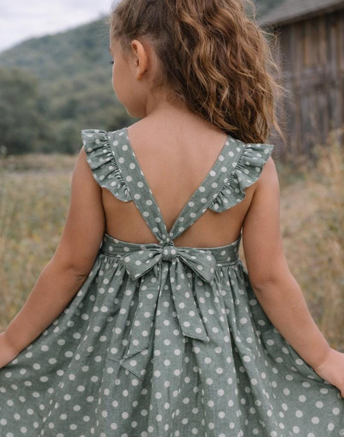 Back view of girl wearing sage green polka dot dress with bow and ruffle straps - Alice Apparel