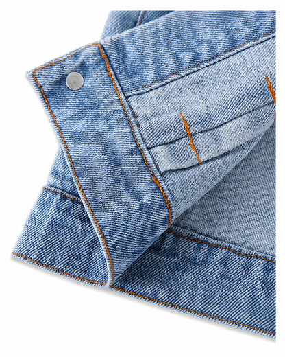 Close-up of washed denim fabric, contrast stitching and button details on a baby jacket