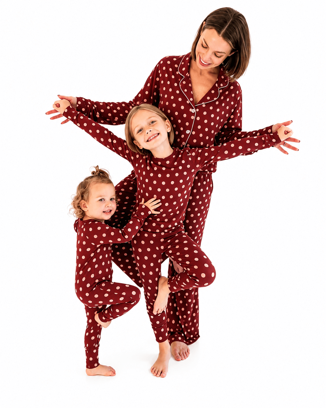 Woman and two girls wearing burgundy polka dot matching family pajamas