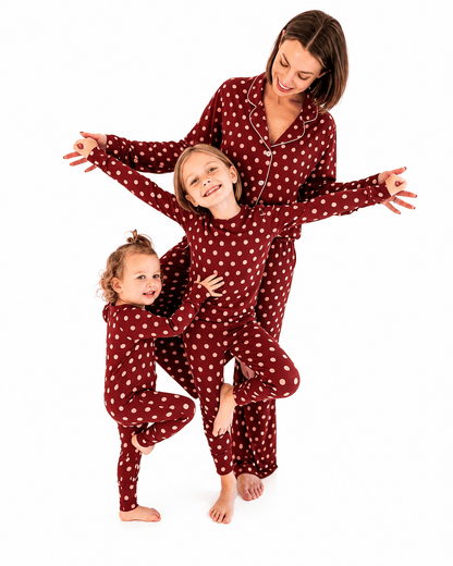 Woman and two girls wearing burgundy polka dot matching family pajamas