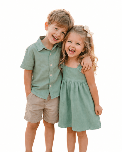 Boy and girl wearing olive green sibling matching outfits with shirt, shorts, and dress