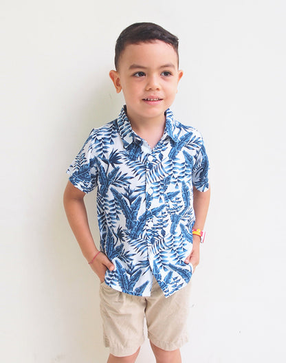 Boy wearing blue palm leaf print short sleeve shirt and khaki shorts - Alice Apparel