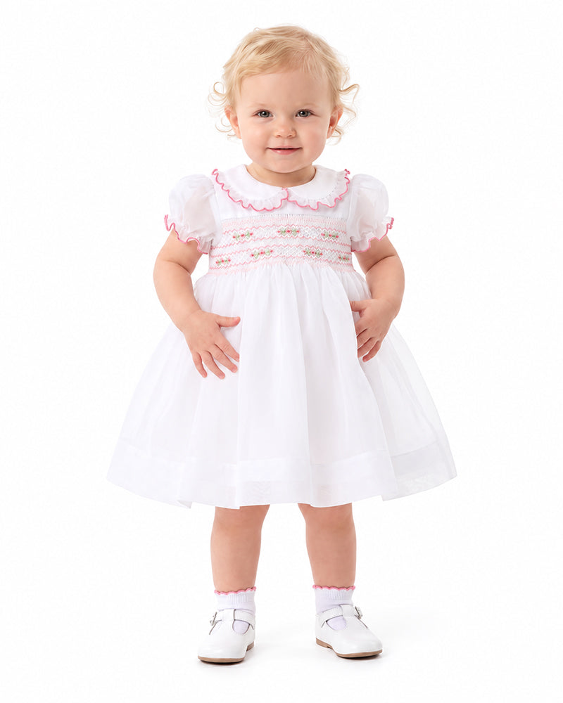 Girl wearing white smocked dress with pink ruffle collar