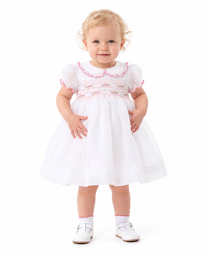 Girl wearing white smocked dress with pink ruffle collar