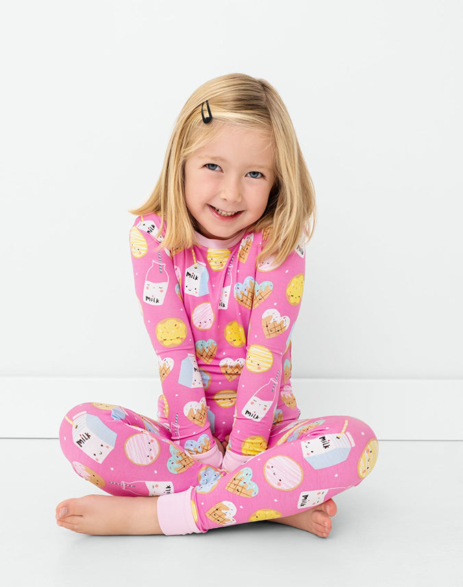 Girl sitting wearing pink milk and cookies print matching pajama set - Alice Apparel