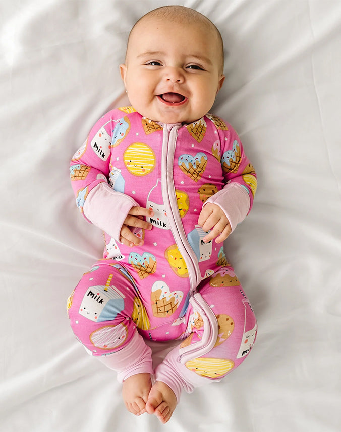 Baby girl lying on bed wearing pink milk and cookies zip pajama set - Alice Apparel