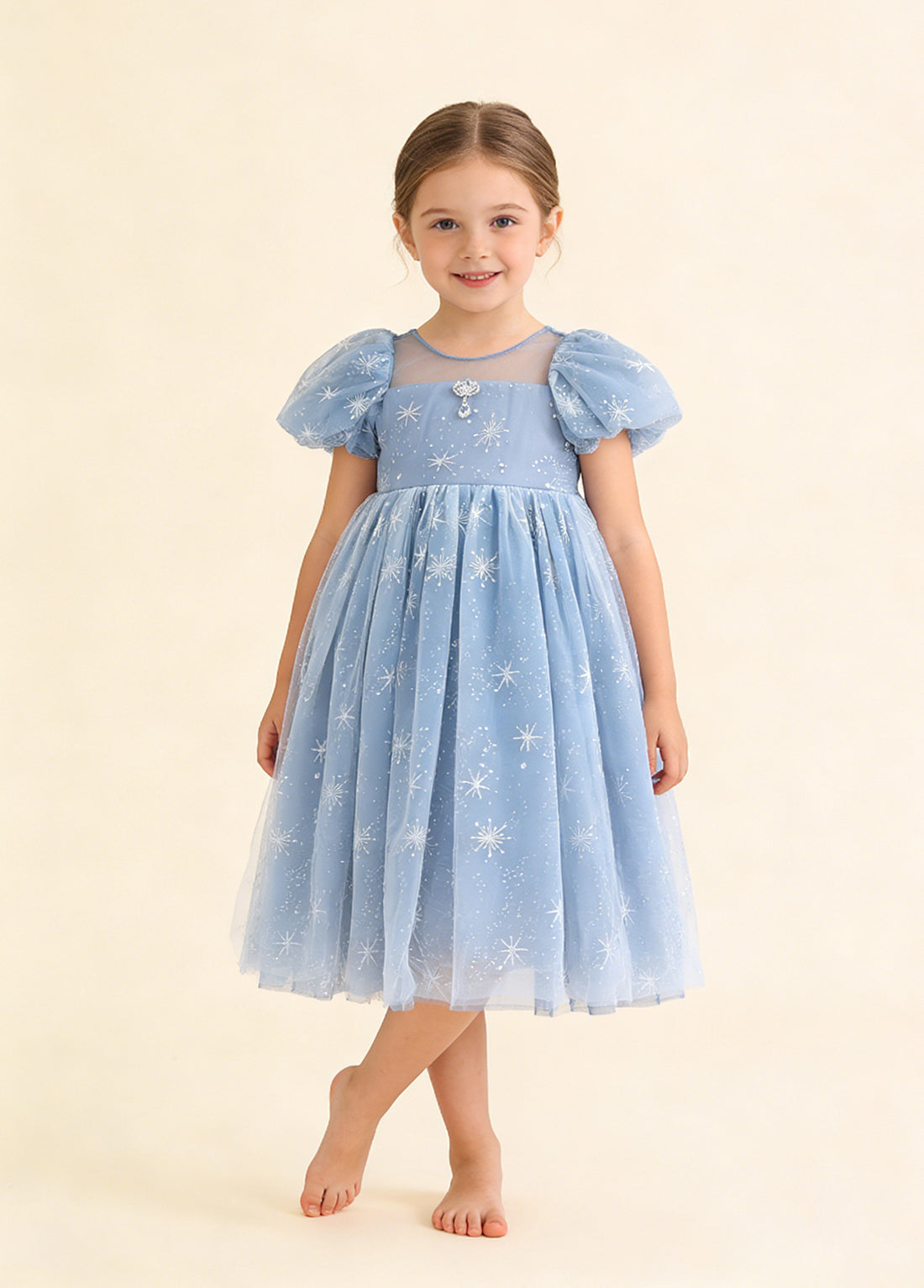Girl wearing a blue snowflake tulle party dress with short puff sleeves